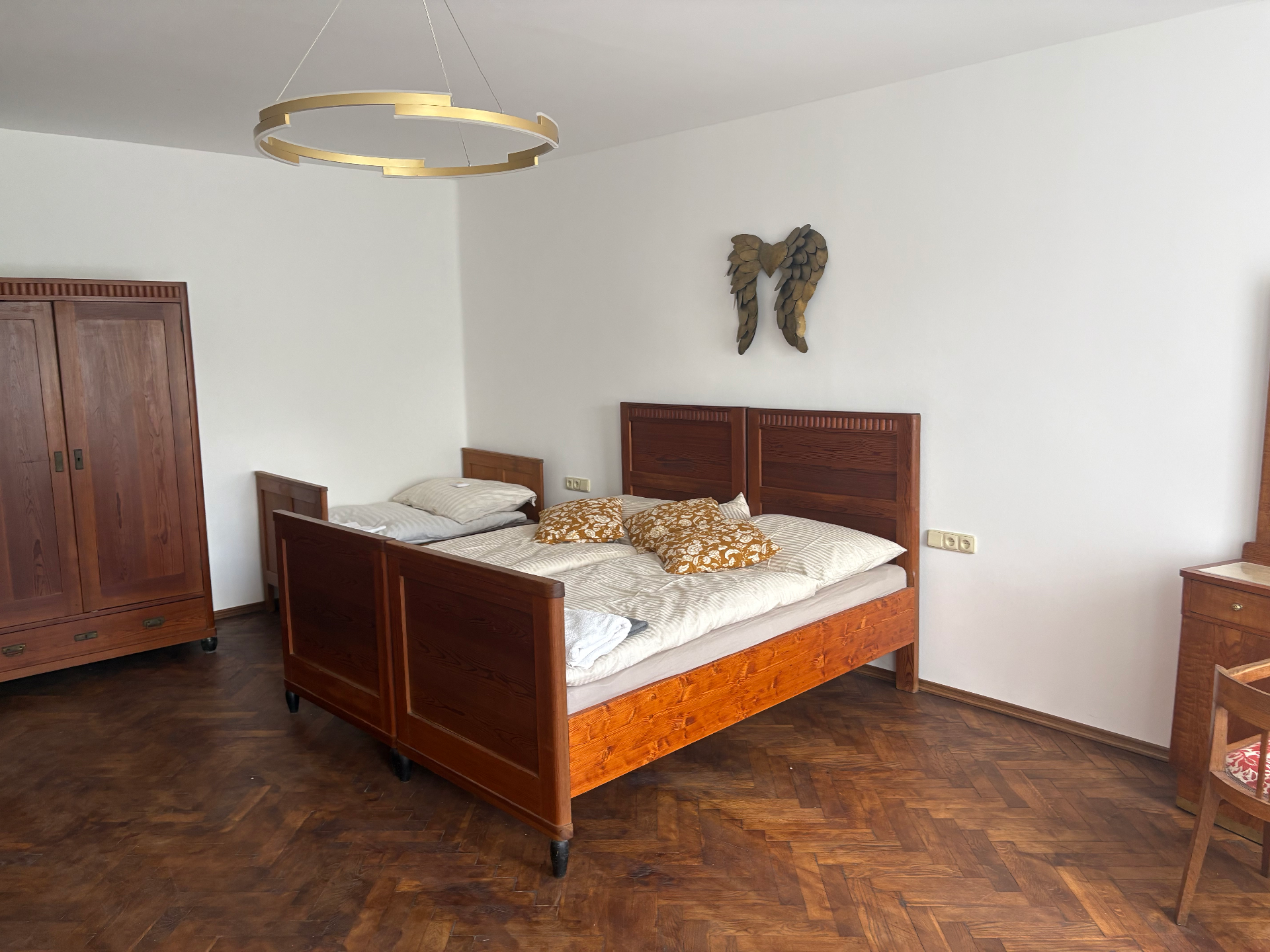 Svatební apartmán s dřevěným nábytkem, dvěma postelemi a parketovou podlahou